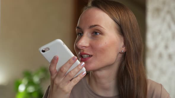 A Young Female User Holding a Mobile Phone in Her Hand Speaks on a Speakerphone Using a Virtual