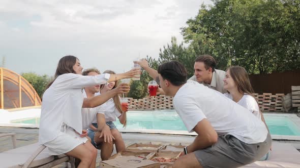 Small company gathered together near poolside. They are eating, drinking and have fun together