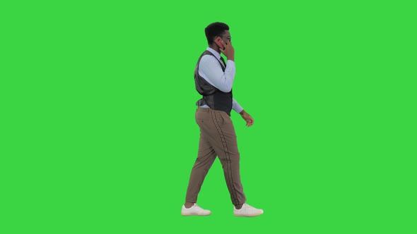 Smiling Young African American Business Man Talking on the Phone While Walking on a Green Screen