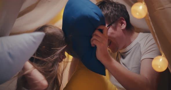 Happy Father and Daughter Playing Pillow Fight in Teepee at Home