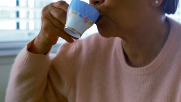 Senior woman having coffee in living room