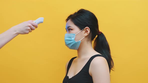 Health-care Worker, Doctor Checks Temperature of Young Asian Woman. Medical Test for Coronavirus