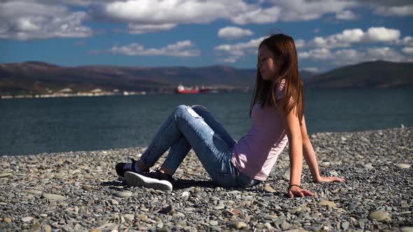Young and Very Attractive Girl Lean Back on the Beach and Look in Camera in Slow Motion. Autumn