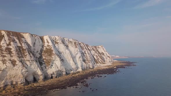 Drone flies low towards the White Cliffs of Dover with beautiful turquoise sea in the foreground.