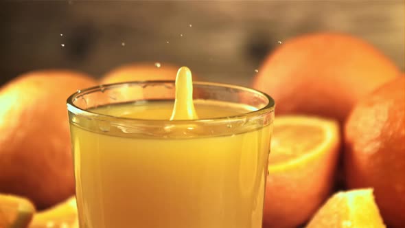 A Drop of Orange Juice Falls Into a Full Glass of Spray