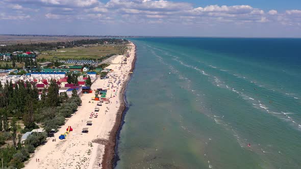 Beautiful flight in summer over the beach. People are resting near the sea. Houses for tourists.