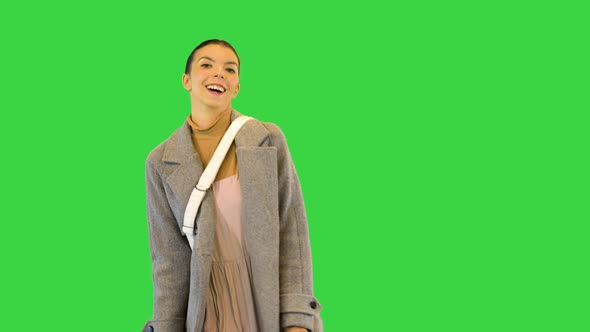 Young Woman in Stylish Clothes Dances with Colored Paper Bags and Smiles on a Green Screen Chroma