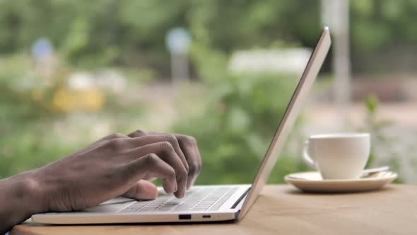 African Hands Typing on Laptop Keyboard Outdoor