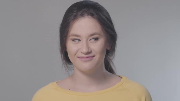 Close-up Portrait of Joyful Caucasian Girl Looking To Both Sides and Winking at Camera