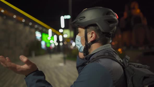 Cyclist in Helmet and Protective Mask Commuter with Bicycle on Way Home From Work Talking on Phone