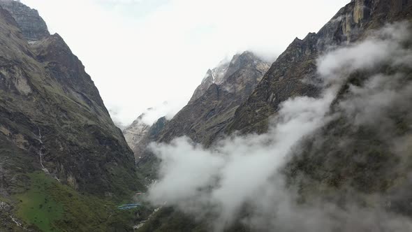 Pan aerial drone shot of a foggy cliffside in the Annapurna mountains, Nepal