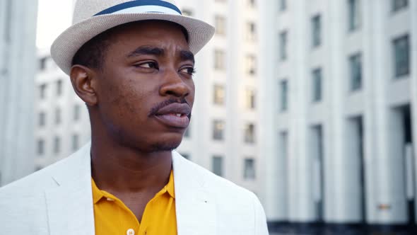 Concentrated African American man in white suit with fedora hat