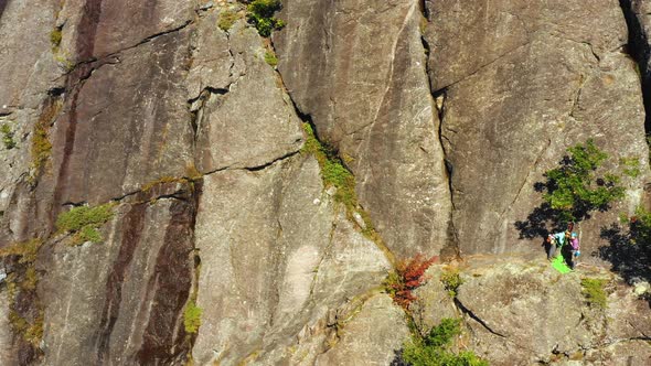 Aerial footage SLIDE right past pair of climbers on a cliff in Maine