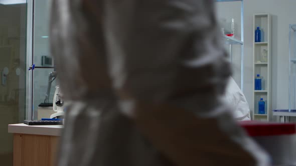 Chemist with Coverall Looking at Virus Test in Equipped Lab