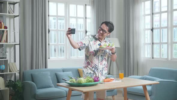 Smiling Asian Man Holding A Dish Of Healthy Food And Taking Selfie With Smartphone