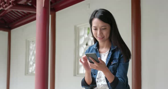 Woman use of mobile phone in Chinese garden