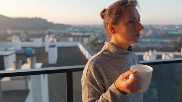 Woman Starts Her Day with a Cup of Tea or Coffee on the Balcony at Dawn