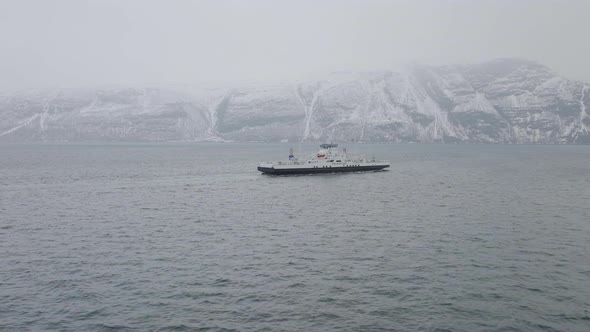 Drone shot orbiting a small ferry boat sailing on the coast of Norway