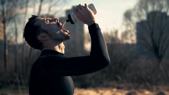 Runner Drinking Water From Bottle. Tired Triathlete Jogger Relaxing After Intensive Workout.