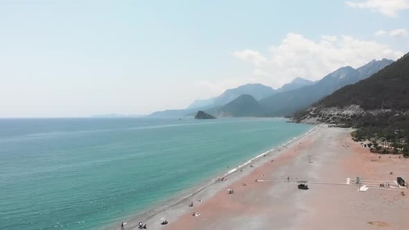 Amazing seashore with wide sandy beach, clear turquoise water and mountains. 