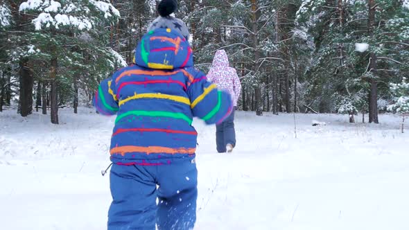 A Small Child Runs After His Mother Through a Snowy Forest or a Park on a Cold Winter Day