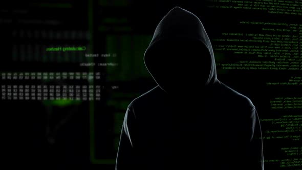 Faceless Male Hacker in Hoodie Standing in Front of Animated Computer Code