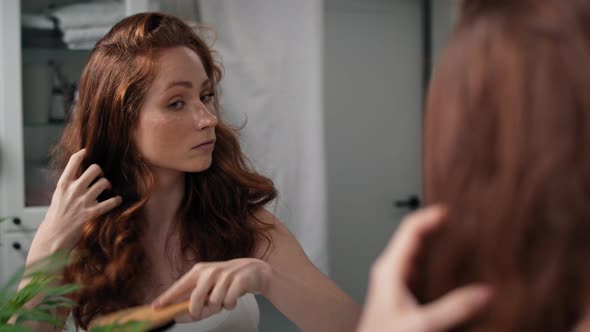 Redhead woman brushing hair in the bathroom. Shot with RED helium camera in 4K.