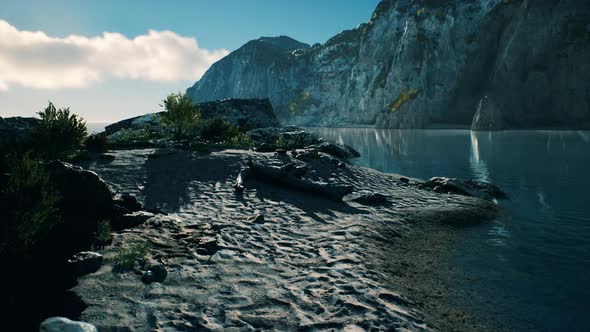 Sandy Beach in Bay Surrounded By Steep Mountains in Sunset