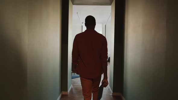 African American Man Walking through Corridor and Entering Office