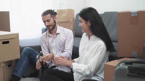 Moving To a New Apartment a Young Couple Sitting on the Floor Near Boxes of Things Talking and