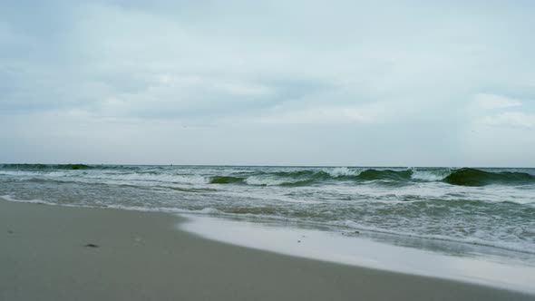 Waves Crashing Sand Beach on Grey Cloudy Weather