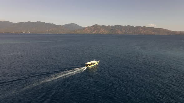 Tourist ferry boat driving on ocean from Gili Air towards Lombok during beautiful sunny day.Aerial v
