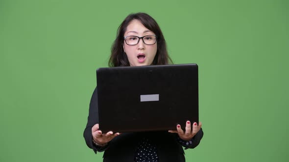 Mature Beautiful Asian Businesswoman Using Laptop Against Green Background