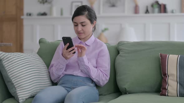 Indian Woman using Smartphone while Sitting on Sofa