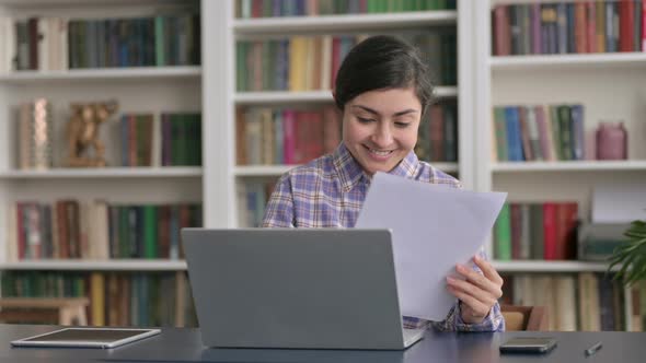 Indian Woman with Laptop Celebrating Success while Reading Documents