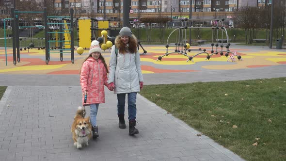 Mother And Daughter Walking With Its Dog At The Park Alley 2