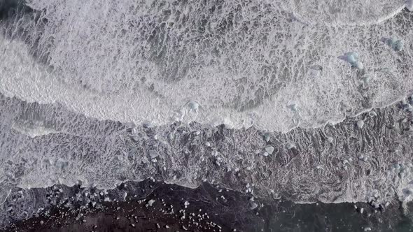 Aerial view of black sand beach with iceberg ice pieces on the shore also cal