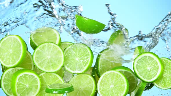 Super Slow Motion Shot of Flying Fresh Lime Slices and Water Side Splash on Light Blue at 1000Fps