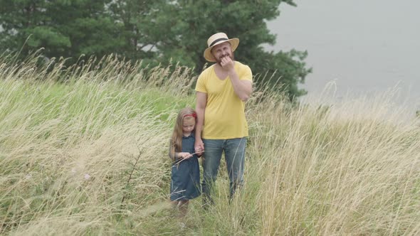 Wide Shot Portrait of Happy Carefree Bearded Man in Straw Hat Holding Hands with Cute Little Girl