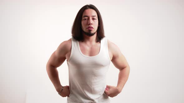 White Male Bodybuilder with Long Brown Hair and Beard Wearing White Tank Top Posing and Flexing