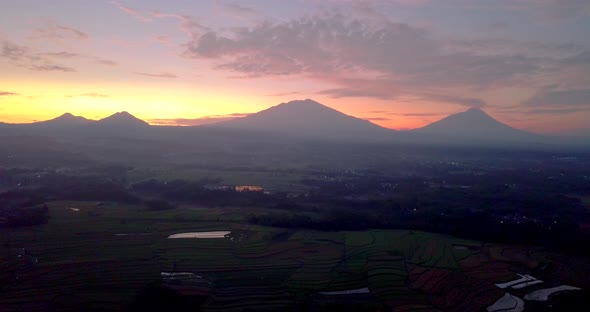 View of Merapi volcano and mounts Merbabu, Andong and Telemoyo during a colorful pink and orange sun