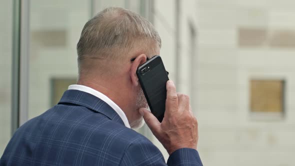 Businessman Talking on the Phone Outside of a Modern Office Building