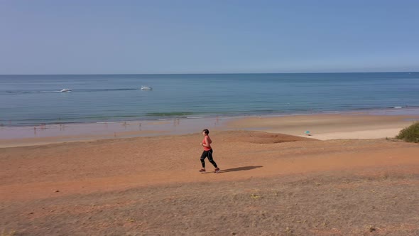 A Middleaged Woman Overweight Trains Cardio Jogging on the Beach for Weight Loss