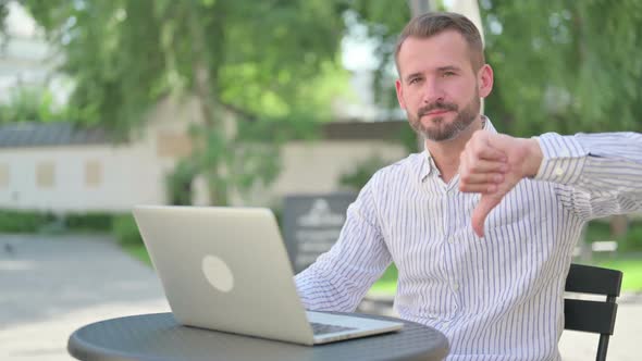 Thumbs Down By Middle Aged Man with Laptop in Outdoor Cafe