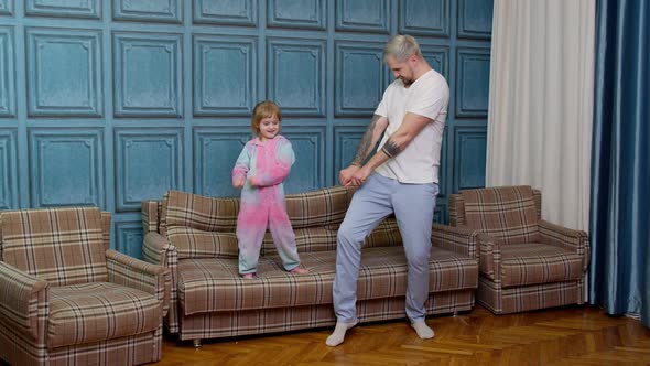 Happy Funny Family Father and Child Kid Daughter Dancing Jumping on Sofa Listening Music at Home