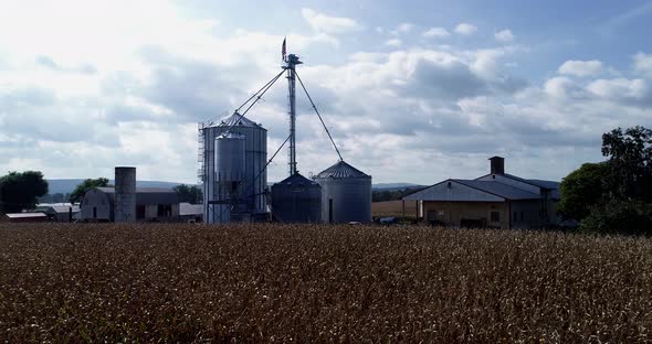 Ascending aerial camera with view of cornfields and grain silos with American flag at the top.