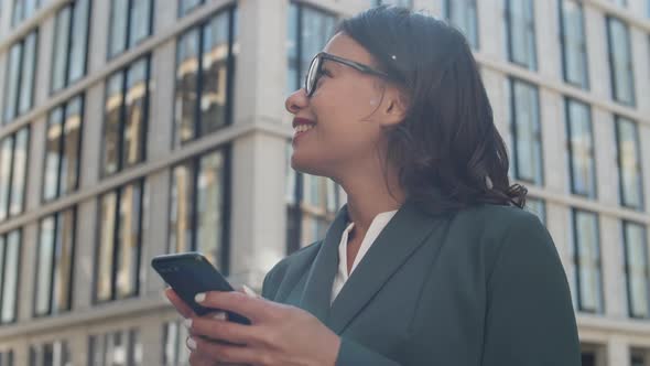 Cheerful Businesswoman Using Cellphone Outside