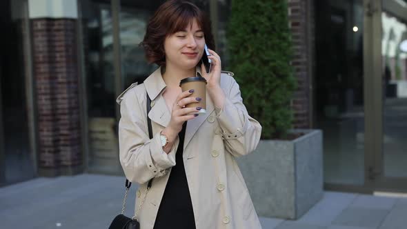 Cute Woman Chatting in Smartphone in Trench Coat