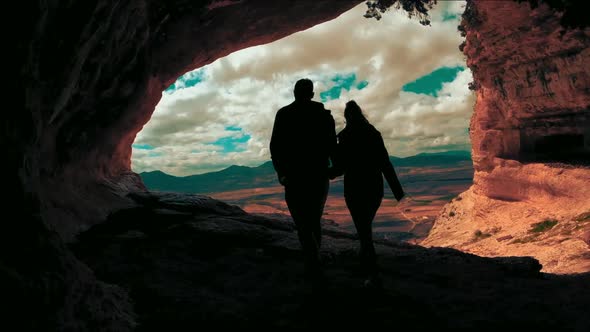 Couple inside cave against landscape. Romantic coupl Scenic rear view