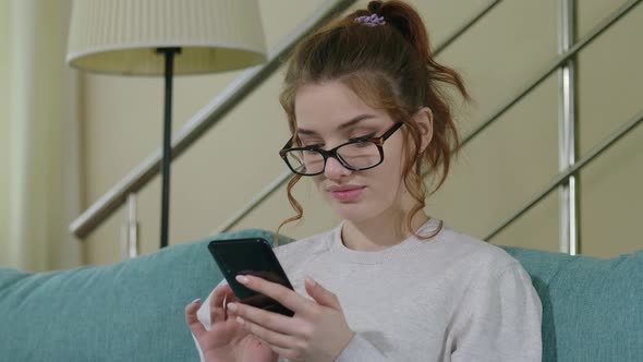 Beautiful Caucasian Woman In Beige Sweater Using Smart Phone Surfing Social Media